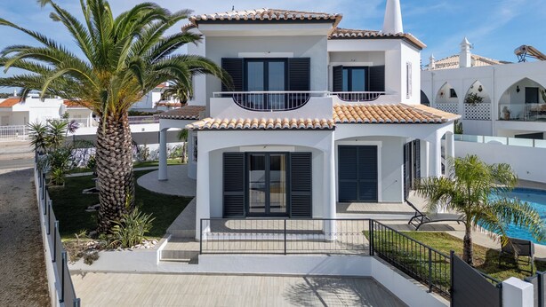 Une maison à deux étages, avec un toit en tuiles, un balcon et une piscine.
