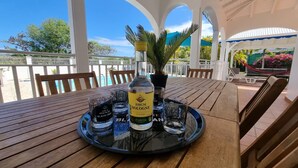 A wooden table with a tray holding a bottle of rum, two glasses, and a water bottle. - COMFORTABLE VILLA WITH PRIVATE POOL  (SAINT FRANCOIS)