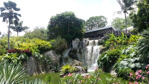 A waterfall surrounded by lush greenery and a traditional building with a tiled roof. - COMFORTABLE VILLA WITH PRIVATE POOL  (SAINT FRANCOIS)