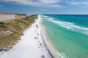 A beach with a row of buildings along the shore, a sandy beach, and the ocean. - Paws, Pedals & Paradise- Golf Cart & Bikes Included! (Inlet Beach)