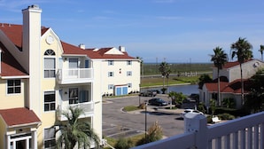 A multi-story building with a parking lot, a view of the ocean, and a clear sky. - Beach Views and Cozy (Corpus Christi)