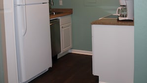 A kitchen with white cabinets, a white refrigerator, a coffee maker, and a dishwasher. - Beach Views and Cozy (Corpus Christi)