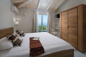 A bedroom with a large bed, wooden wardrobe, and a TV on a shelf. - Exclusive 5* Villa with stunning views and heated pool (Labin)