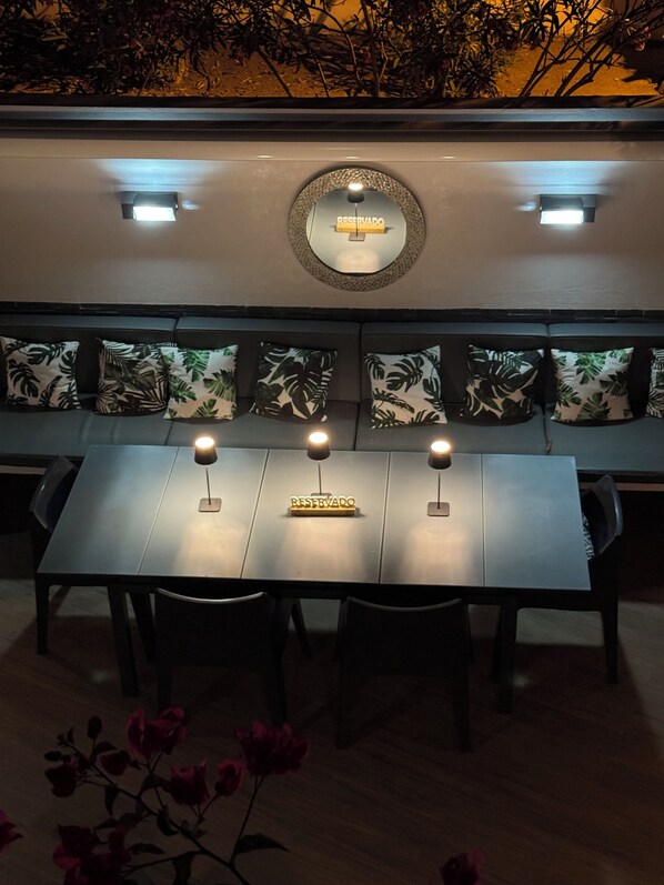 Un espace repas avec une longue table, trois bougies et un panneau indiquant « RESERVÉ ».