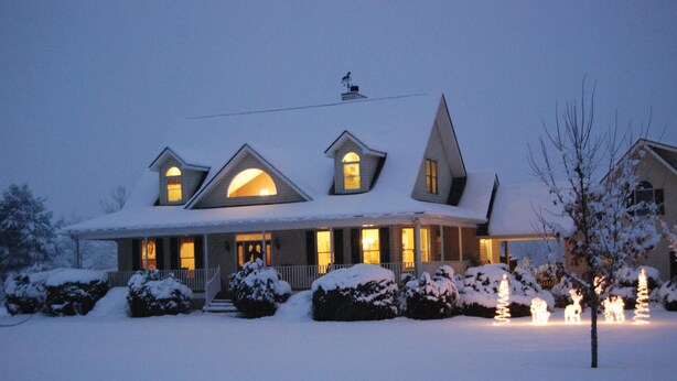 Ein mit Schnee bedecktes Haus mit vielen Fenstern und einer Veranda.