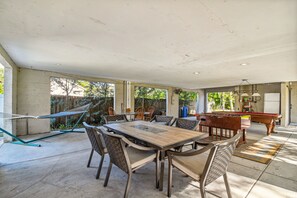 Un amplio patio al aire libre con mesa de billar, asientos cómodos y una hamaca.