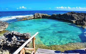 Une mer d’un bleu profond, parsemée de formations rocheuses, et une terrasse en bois.