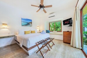 A bedroom with a bed, bedside lamps, a ceiling fan, a TV, a window with a view, and a wooden bench.