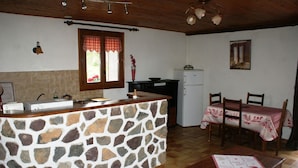 Eine Küche mit einer Steinarbeitsplatte, Holzschränken, einem Kühlschrank und einem Essbereich mit Tisch und Stühlen.