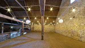Un espacio interior con techo de madera alto, paredes de piedra y suelo de madera.
