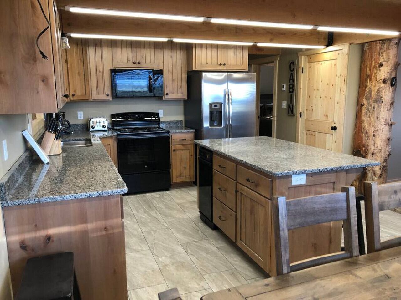 A kitchen with wooden cabinets, a stainless steel refrigerator, a built-in oven, and a granite countertop.