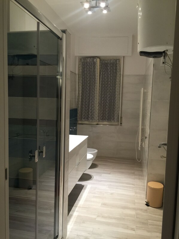 Un baño moderno con cabina de ducha de vidrio, un inodoro y un lavabo.