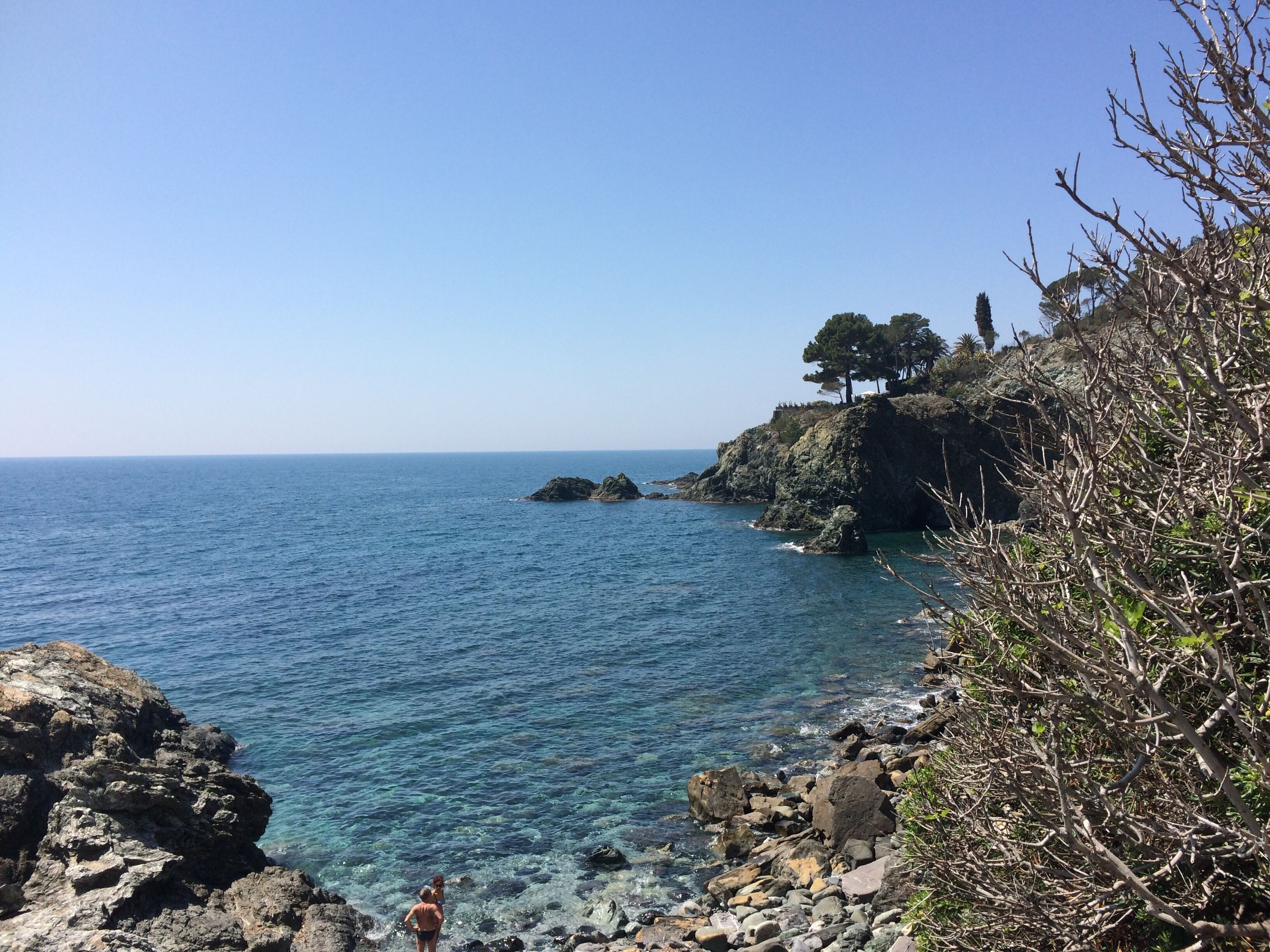 A coastal landscape with rocky terrain and clear blue water.