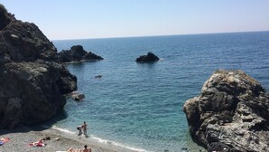 A rocky beach with clear water and a view of the sea.