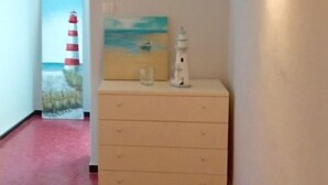 A hallway with a clock, a painting, and a dresser.