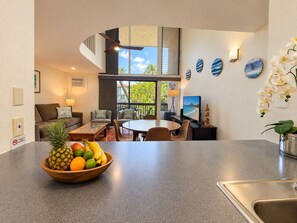 A modern kitchen with a fruit bowl, dining area, and a view of the outdoors.