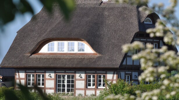 A traditional half-timbered house with a steeply pitched roof and a dormer window.