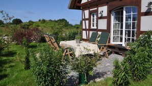 A traditional half-timbered house with a patio area featuring outdoor seating and a stone pathway.
