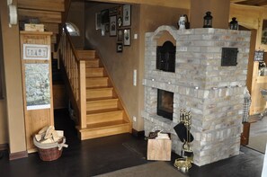 A staircase leading to a wooden floor, a stone fireplace with a mantel, and a basket of firewood. - Rügen-Cottage up to 8 persons, sauna, fireplace,beach chair,barbecue,garden,parking lot  (Dranske OT Lancken)