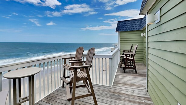 A wooden deck with chairs and a table overlooking the ocean. - Terrapin Tides | Oceanfront + Community Pool! (Kure Beach)