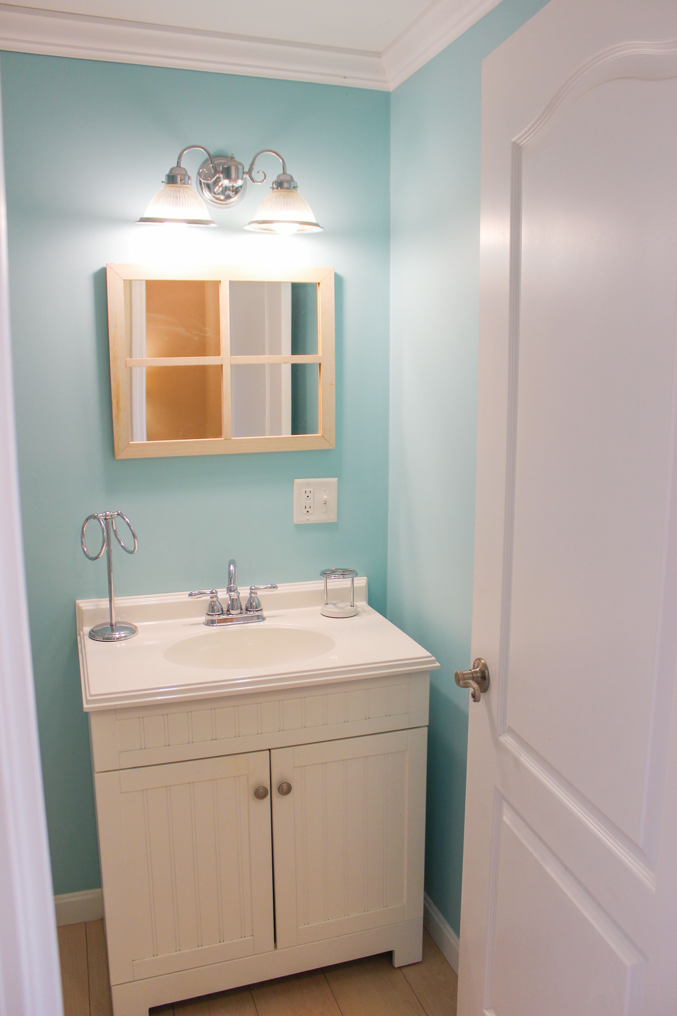 A bathroom with a white vanity, a mirror, and two wall-mounted lights.