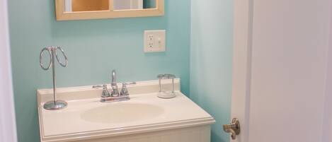 A bathroom with a white vanity, a mirror, and two wall-mounted lights.
