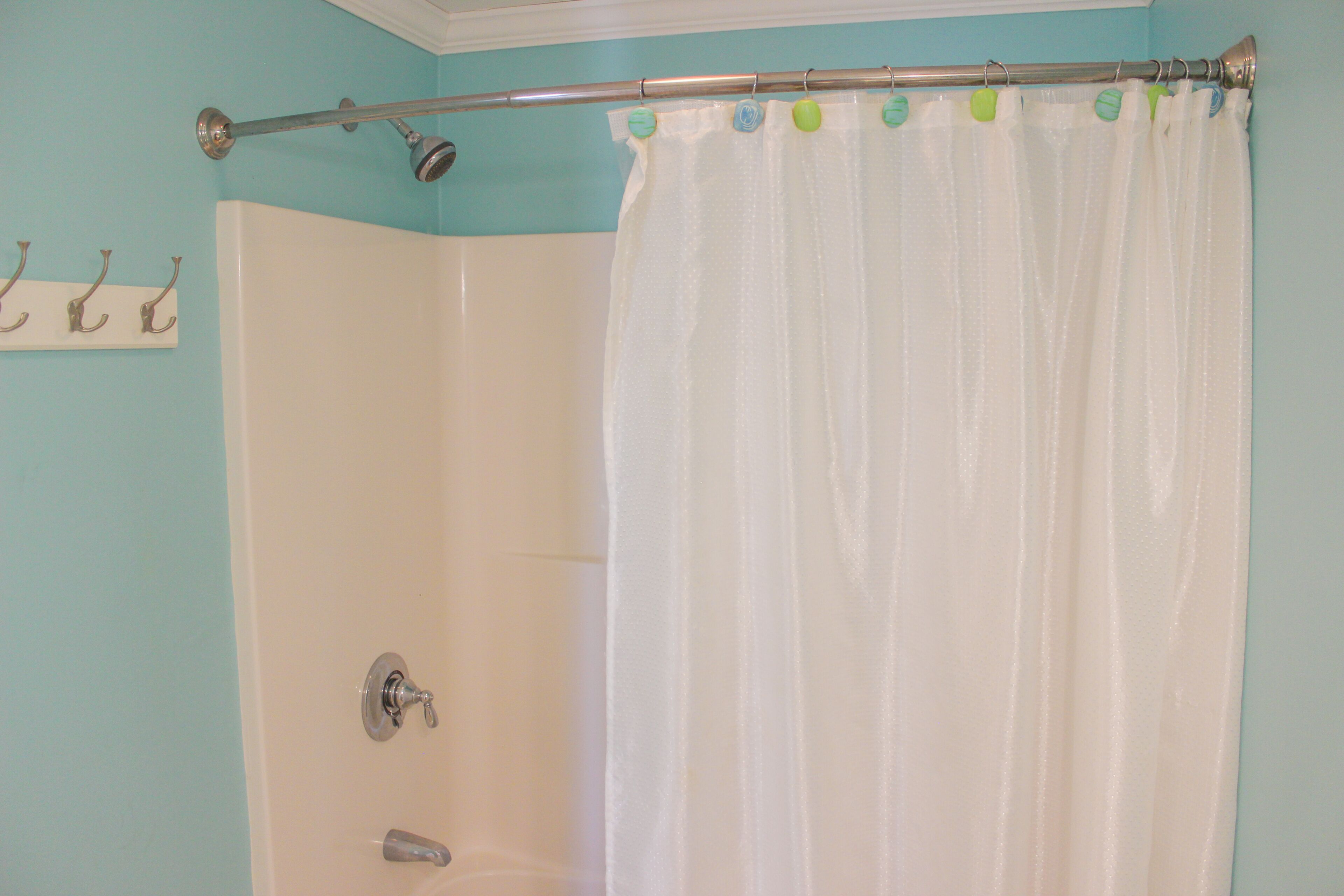 Un baño con cortina de ducha, toallero y cabezal de ducha.