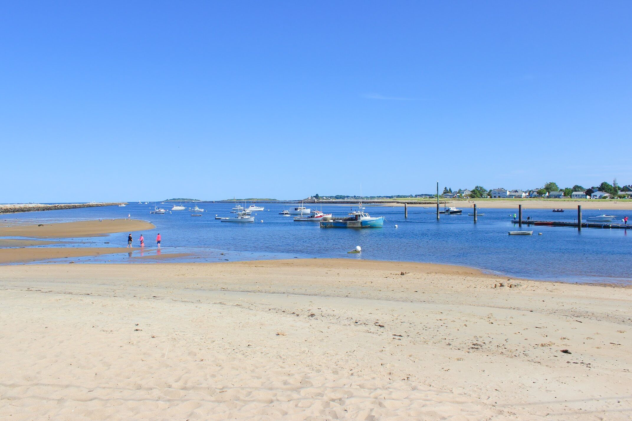 Une plage avec des bateaux amarrés dans l’eau et un ciel dégagé.