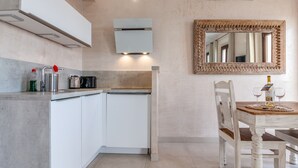 A modern kitchen with white cabinets, a built-in oven, and a coffee maker.
