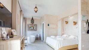 A modern bedroom with a large bed, a bathtub, and a vanity area.