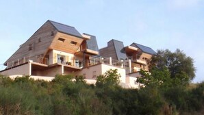 Ein modernes Haus mit Satteldach und großen Fenstern, umgeben von viel Grün.
