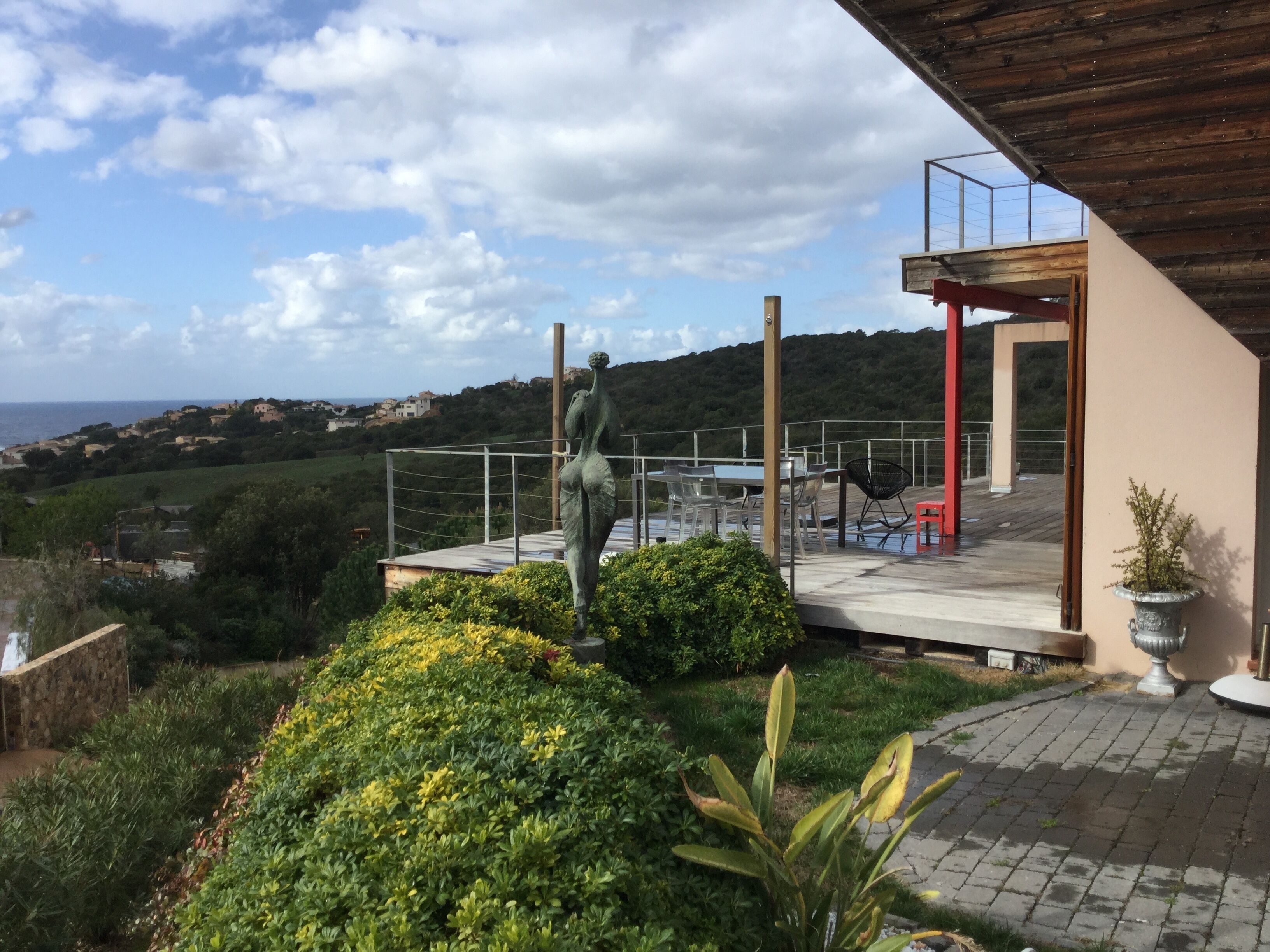 Une terrasse avec vue sur la mer, une statue et un espace repas.