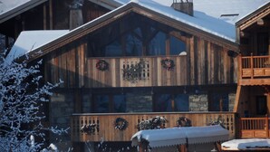 Eine Holzhütte mit Steinverkleidung, geschmückt mit Kränzen, und einem Schild, das auf eine Ferienwohnung hinweist.