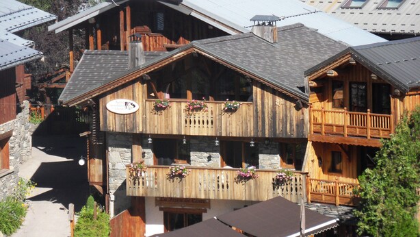 Ein Holzbalkonbau mit Balkonen, einem Hinweisschild für einen Skigebiet und Außenbereich-Sitzmöglichkeiten.