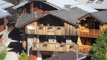 Un bâtiment en bois doté de balcons, d’un panneau indiquant l’emplacement d’une station de ski et d’un espace extérieur aménagé pour s’asseoir.