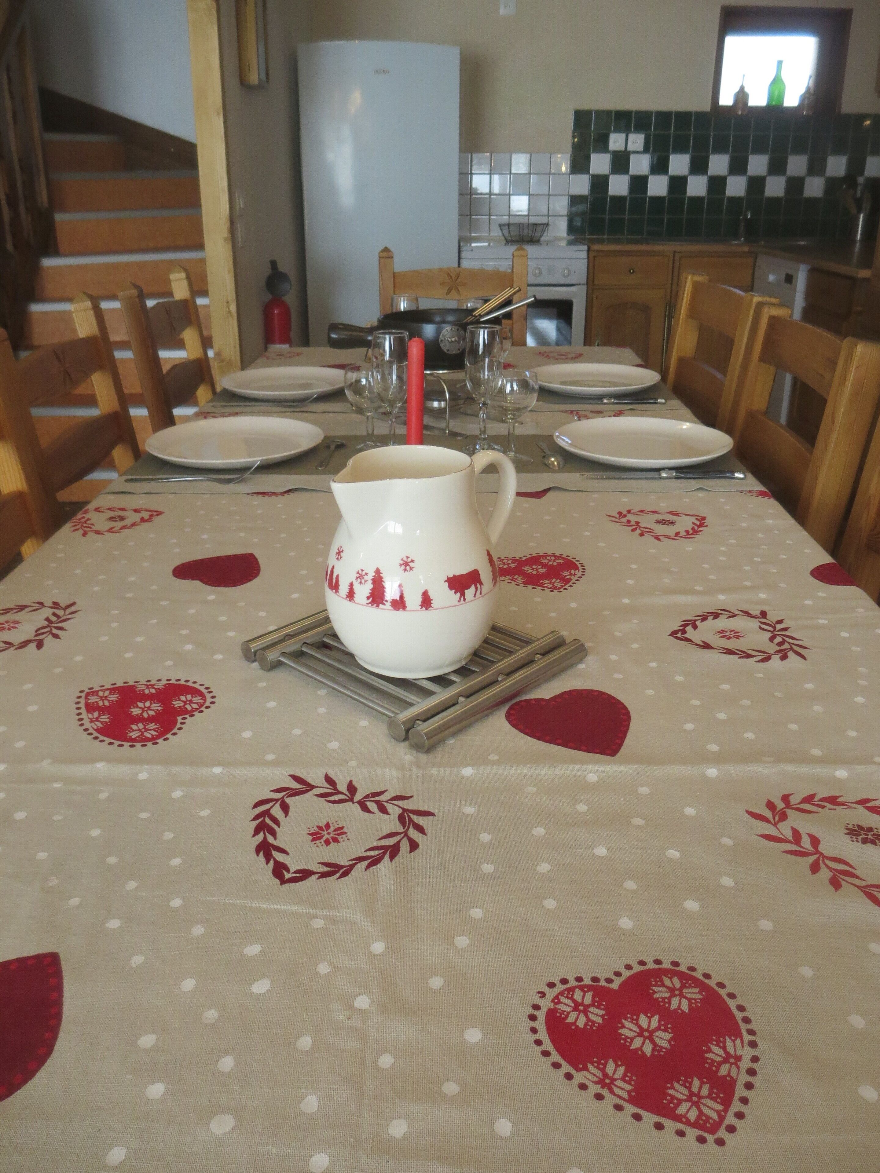 Une table à manger dressée avec des assiettes, un pichet et une bougie.