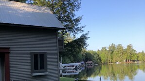 A house with a dock extending into a calm lake, surrounded by trees. - Adirondack Beauty! 110 ft Lake Frontage On Brant. Lake - Beach; Kayaks, Canoes (Greig)