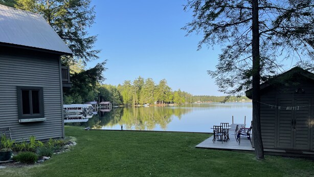 A lakeside property with a dock, a small building, and a grassy area. - Adirondack Beauty! 110 ft Lake Frontage On Brant. Lake - Beach; Kayaks, Canoes (Greig)