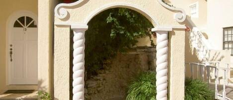 A traditional Mediterranean-style entrance with a white archway, stone steps, and a tiled patio.