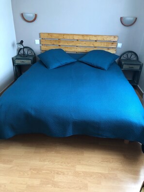 A bed with a wooden headboard, two nightstands, and a blue bedspread.