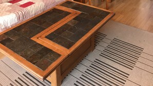 L’intérieur d’un chalet confortable, avec des murs en rondins de bois, une table à manger en bois, des chaises, un canapé matelassé et une table basse recouverte de carreaux de pierre.
