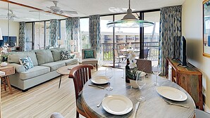 Een eethoek met een ronde tafel voor vier personen, een bank en een balkon met buitenmeubels.