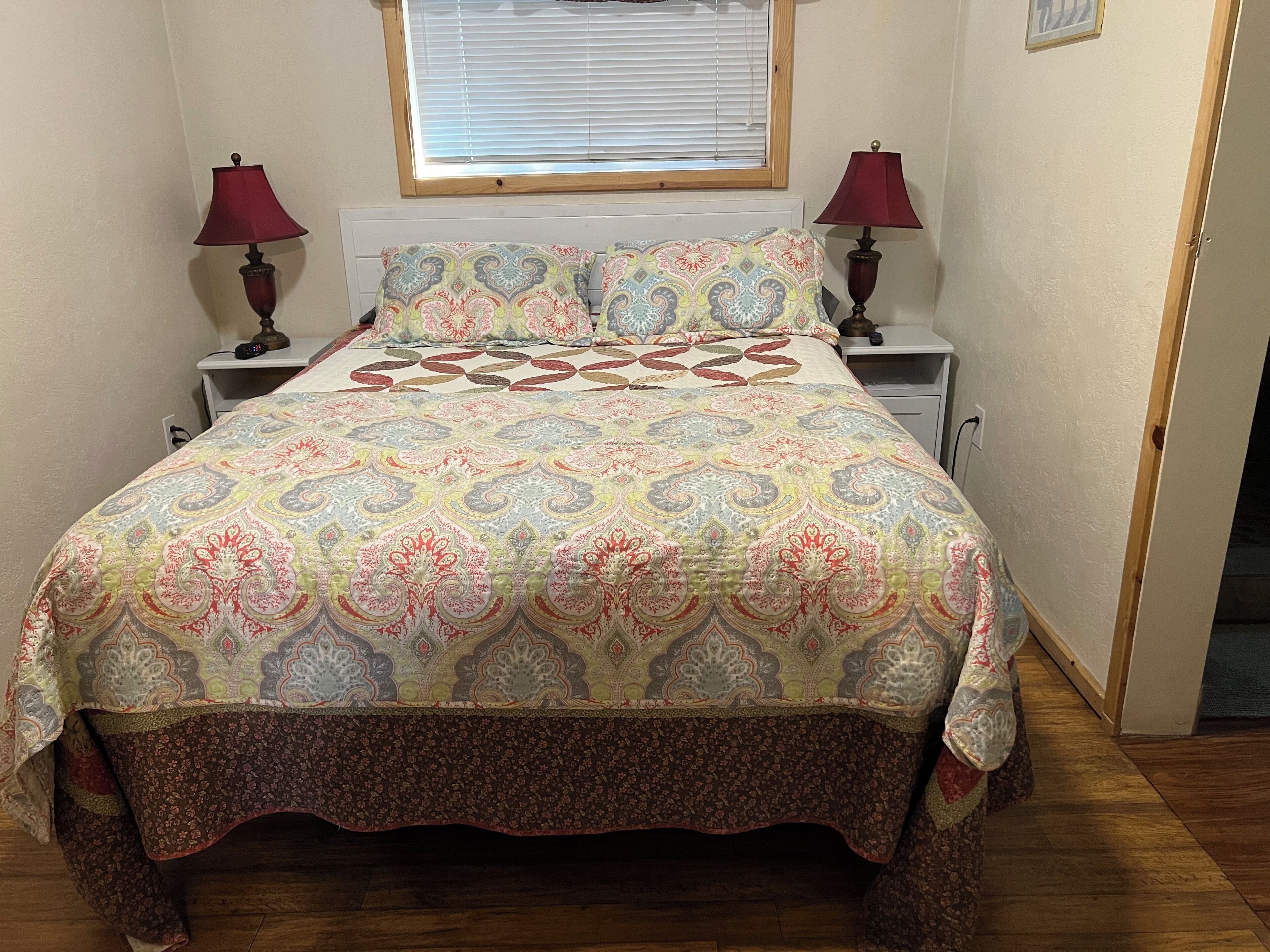 Una camera da letto con un letto, due comodini, una finestra con tende e una porta.