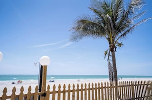 Ein Strand mit einer Holzzaun, einer Palme und blauem Himmel.