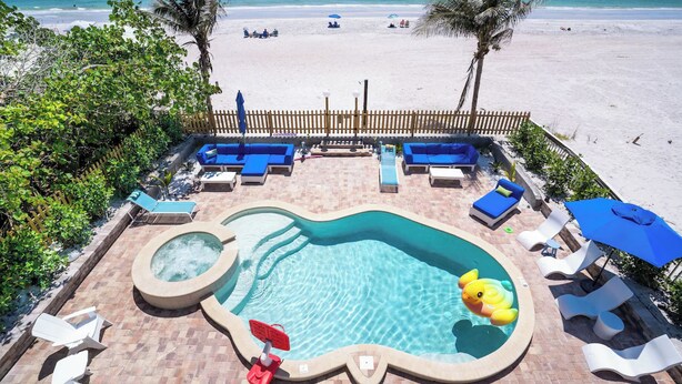 Un espace piscine avec des chaises longues, un jacuzzi et une vue sur la plage.