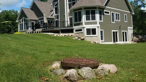 A large, two-story house with a prominent chimney, large windows, and a deck area. - Elegant 2 King Bedroom Apt - 2 night minimum - 4 adults  (Traverse City)