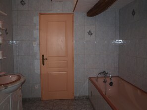Un baño con puerta de madera, lavabo y bañera.