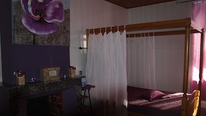 Une chambre à coucher avec un lit à baldaquin, une coiffeuse avec un miroir et un grand tableau représentant des motifs floraux accroché au mur.