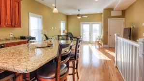 A spacious kitchen with a large island, wooden cabinets, and pendant lighting.