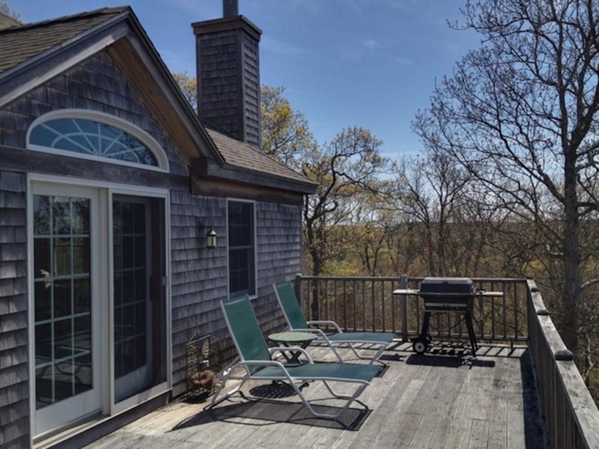 Una terraza de madera con mobiliario exterior, una parrilla y una chimenea.